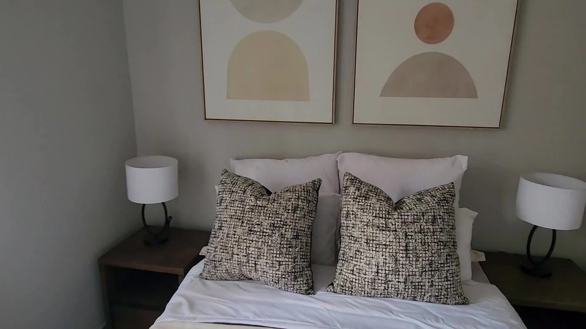 Show-unit bedroom with patterned cushions and framed prints, from an apartment walkthrough